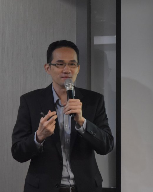 Johnny Wang speaking at a self-publishing seminar, holding a microphone